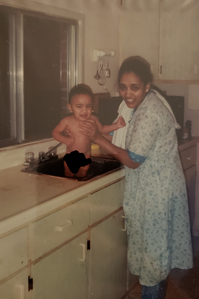 Picture of Bilal's mom holding him in the kitchen sink.